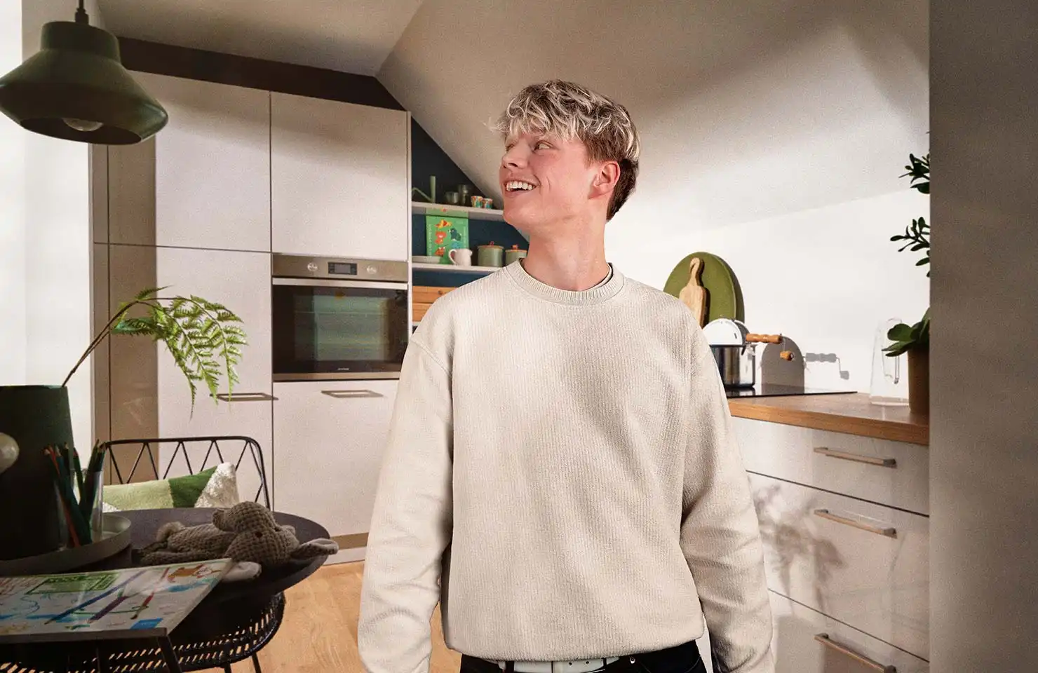 Ein junger Mann mit einem weißen Pullover schaut sich seine neue Nolte Küchen an